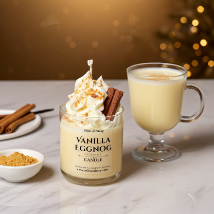 Vanilla eggnog candle with whipped cream and a cinnamon stick, next to a glass of eggnog on a marble surface.