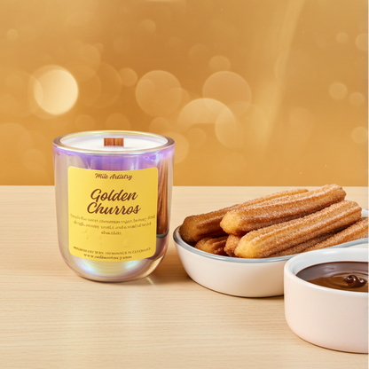 Candle labeled 'Golden Churros' next to a bowl of churros and a bowl of chocolate sauce on a wooden surface with a warm, blurred background.