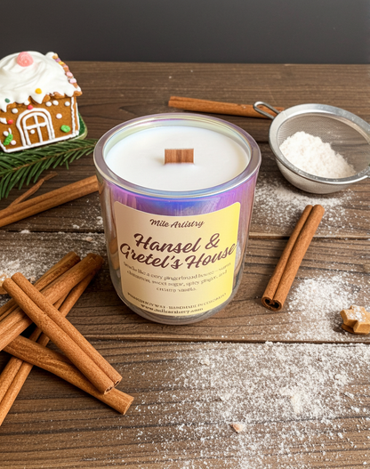 Candle labeled 'Hansel & Gretel's House' on a wooden surface with cinnamon sticks and a gingerbread house.