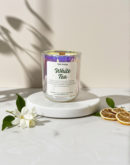 White tea candle on a marble surface with flowers and dried oranges
